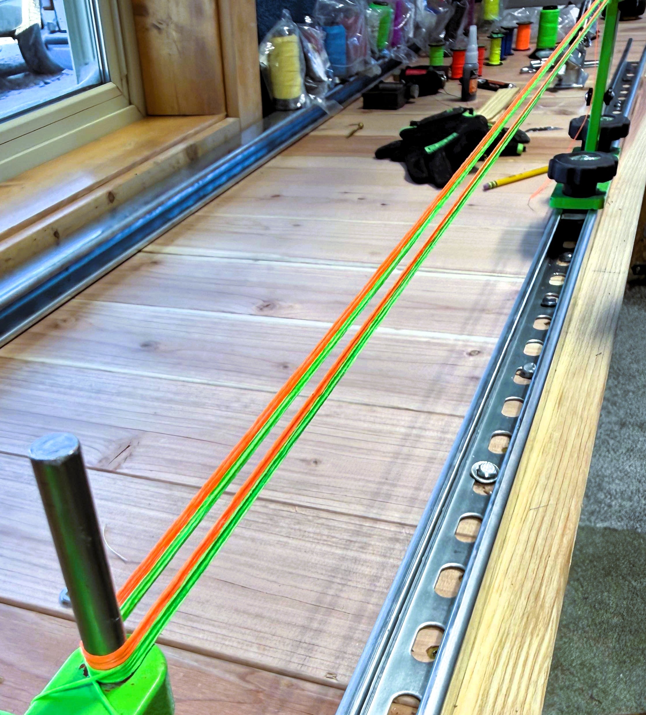 Wooden workbench with custom bowstrings and spools of string material in different colors